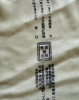 Textured fabric with printed text and a logo on a beige background