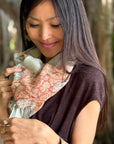 Woman holding a map-patterned scarf with a blurred natural background