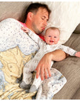 Man and baby lying on a couch together, both wearing matching pajamas.