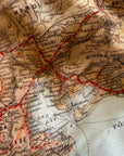 Close-up of a vintage map with red lines and black text on a beige background