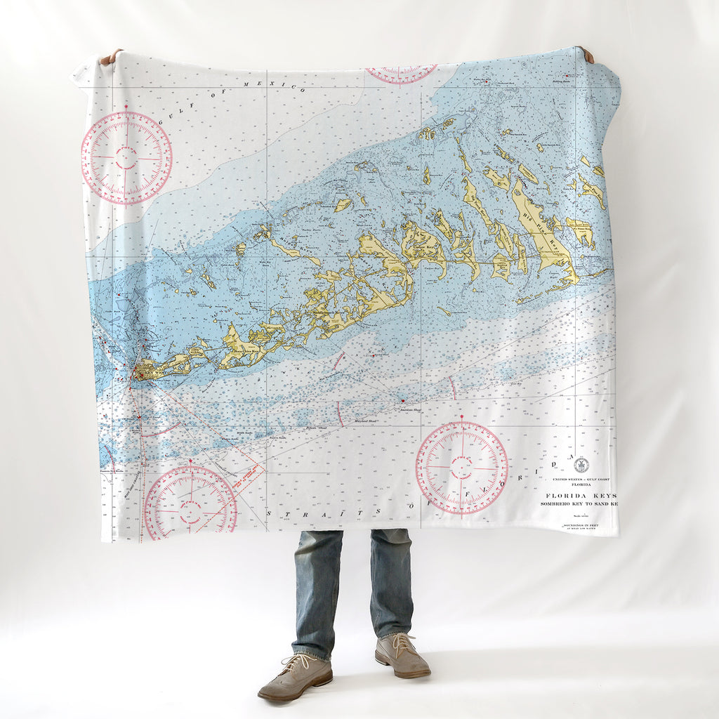 A person standing with a nautical chart blanket draped over their shoulders, displaying detailed map patterns.