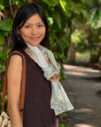 Woman standing outdoors with greenery in the background