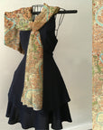 Black dress with a map-patterned scarf draped over a hanger against a white wall.