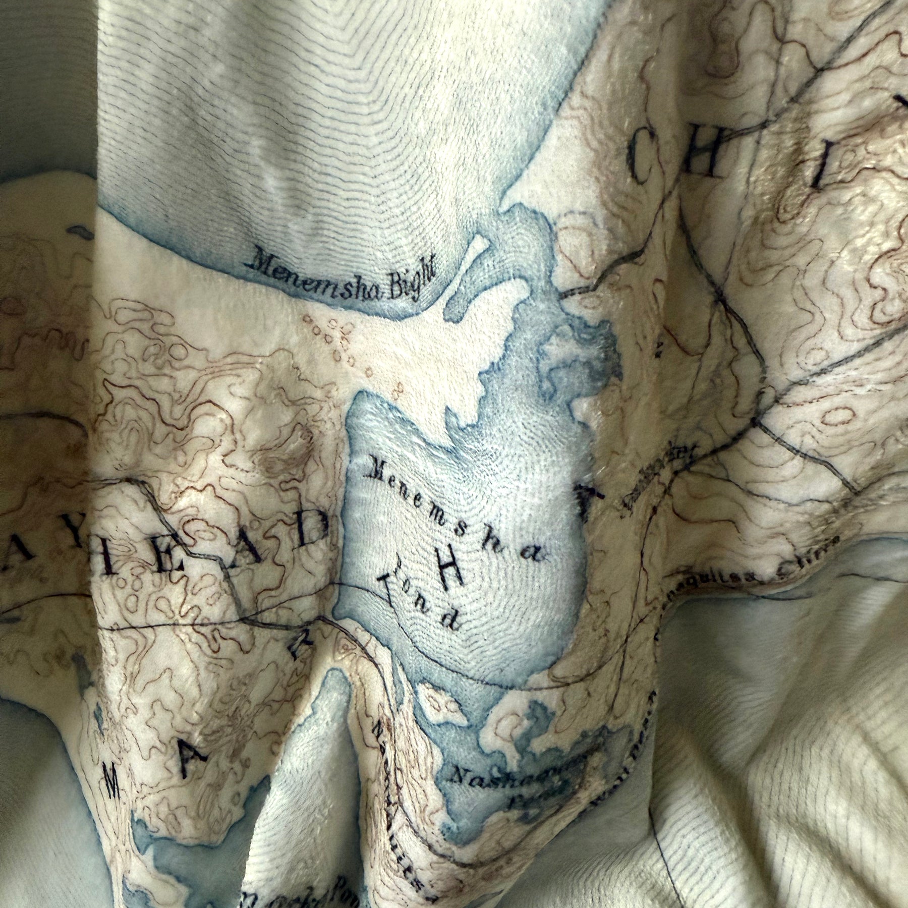 Close-up of a textured fabric with a map design featuring water bodies and landforms.
